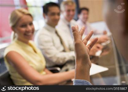 Five businesspeople at boardroom table with focus on businessman&acute;s hand