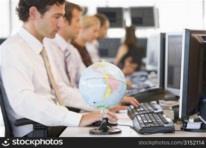 Five businesspeople in office space with a desk globe in foreground