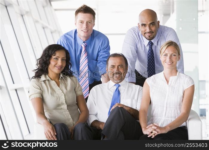 Five businesspeople indoors smiling (high key/selective focus)