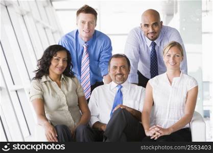 Five businesspeople indoors smiling (high key/selective focus)