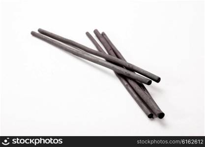 Five charcoal sticks lie together on a white background.