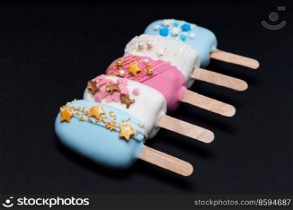 Five decorated cake pops ice creams in a row on black background. decorated cake pops ice creams on black background