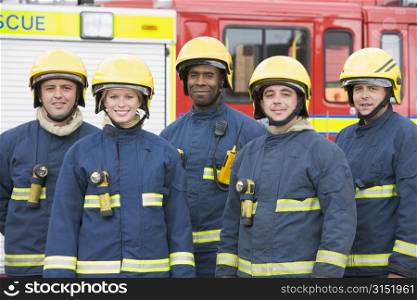 Five firefighters standing by fire engine wearing helmets