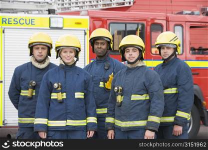 Five firefighters standing by fire engine wearing helmets