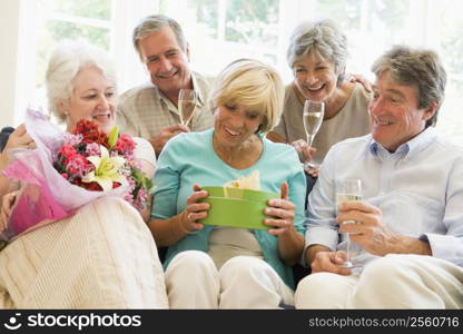Five friends with champagne and gifts in living room smiling