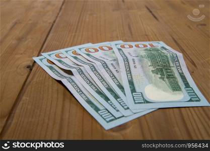 five hundred dollar bills lying on a rough wooden surface. five hundred dollars