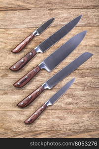 five kitchen knifes over brown wooden table