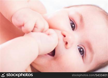 Five month old baby is sucking her fists. Close up face