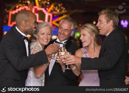 Five people in casino toasting champagne smiling (selective focus)