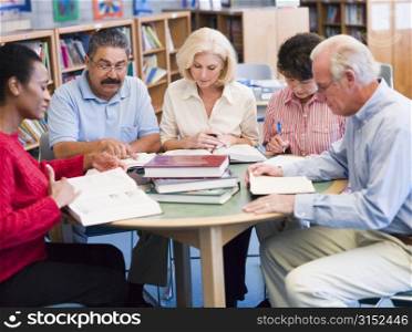 Five people sitting in library with books and notepads (selective focus)