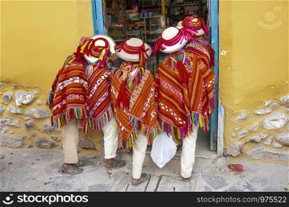 Five peruvian kids dressed with typical Peru clothes waiting outside a grocery store