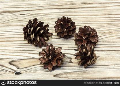 Five pine cones lie on a wooden surface