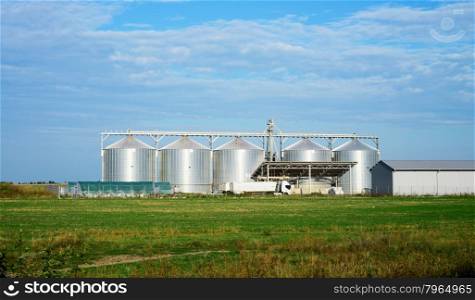 five silver silos in field under blue sky