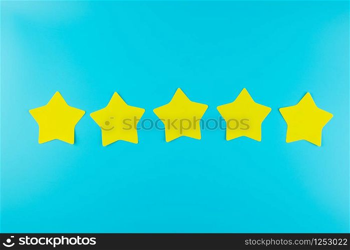 five star yellow paper note on blue background with copy space for text. Customer reviews, feedback, rating, ranking and service concept.