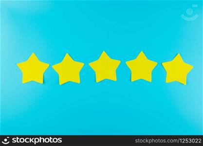 five star yellow paper note on blue background with copy space for text. Customer reviews, feedback, rating, ranking and service concept.