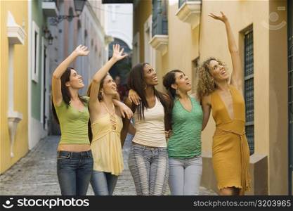 Five teenage girls standing together and waving
