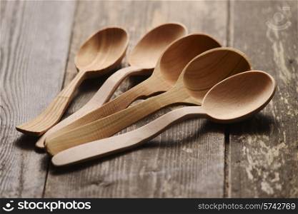five wooden spoons on a dark wooden background
