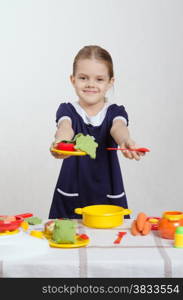 Five year old girl playing in a children&#39;s mistress dishes at a table covered with a cloth