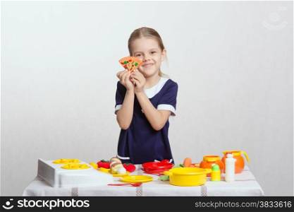 Five year old girl plays children&#39;s dishes at a table covered with a cloth