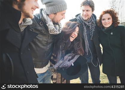 Five young adult friends laughing together in park