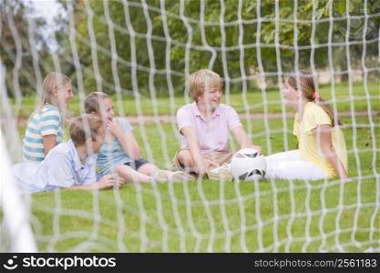 Five young friends on soccer field talking and smiling