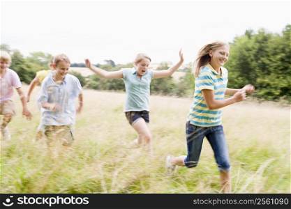 Five young friends running in a field smiling