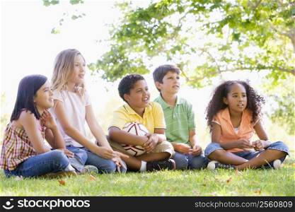 Five young friends sitting outdoors with soccer ball