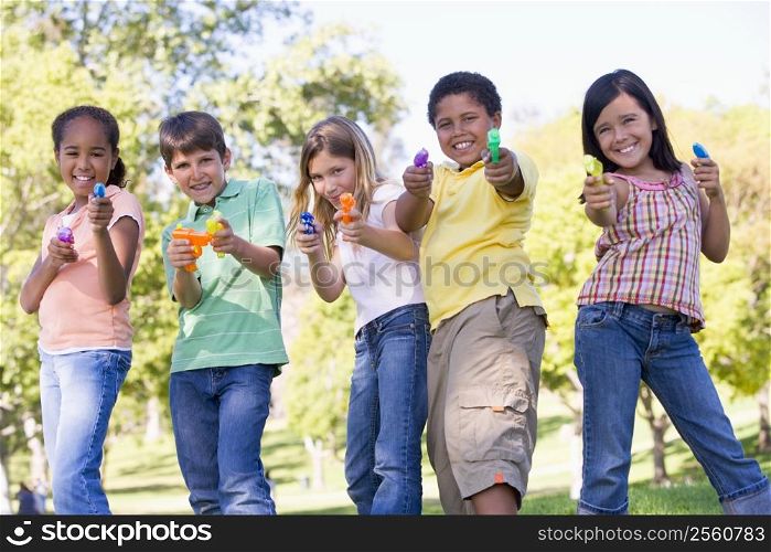 Five young friends with water guns outdoors smiling