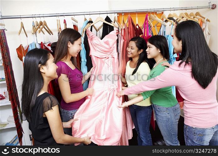 Five young women looking at a dress in a clothing store