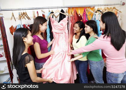 Five young women looking at a dress in a clothing store