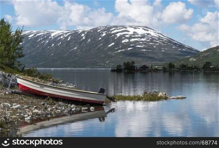 fjord in norway in the summer with boat on trailer and mountains with snow as background