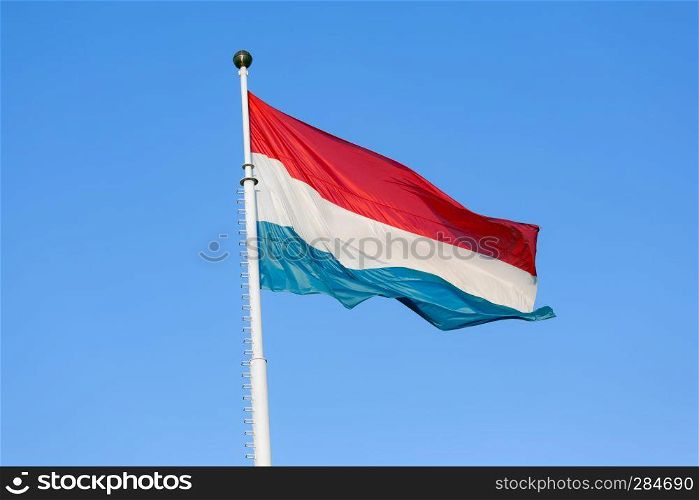 Flag of Luxembourg waving in the wind against a blue sky. Flag of Luxembourg waving in the wind against blue sky