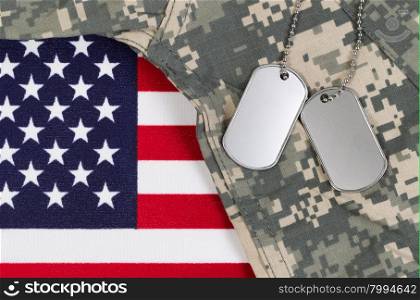 Flag of the United States of America with military identification tags, neck chain, and combat uniform top. Military service concept.