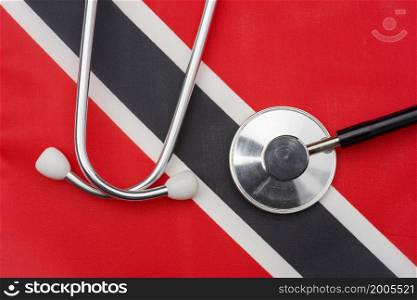 Flag of Trinidad and Tobago and stethoscope. The concept of medicine. Stethoscope on the flag in the background.. Flag of Trinidad and Tobago and stethoscope. The concept of medicine.