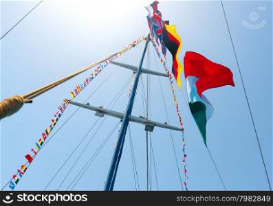Flags of different countries on the mast of sailboat