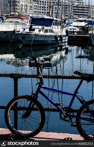 Flaked bicycle on the embankment of Valletta. Yachts docked at the port of Malta.