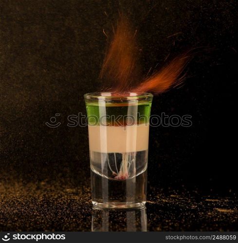 flaming cocktail with cinnamon in a shot glass on a black background, isolated. shot glass with alcohol on a dark background