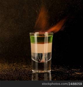 flaming cocktail with cinnamon in a shot glass on a black background, isolated. shot glass with alcohol on a dark background