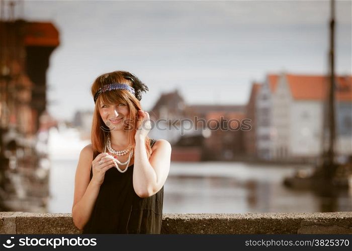 Flapper girl. Retro style fashion vintage woman from roaring 1920s outdoor on the street. Old town Gdansk Danzig in the background