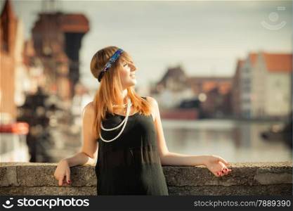 Flapper girl. Retro style fashion vintage woman from roaring 1920s outdoor on the street. Old town Gdansk Danzig in the background