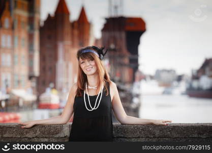 Flapper girl. Retro style fashion vintage woman from roaring 1920s outdoor on the street. Old town Gdansk Danzig in the background