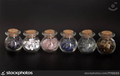 flask with gems in front of black background