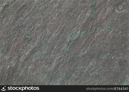 flat, gray, fine-grained, foliated slate rock with purple tint and green spots and veins