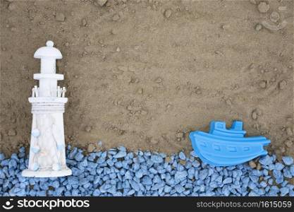 flat lay blue pebbles with lighthouse boat sand