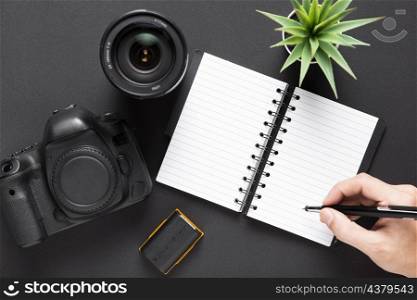 flat lay camera lenses notebook black background