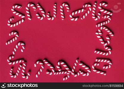 Flat lay Christmas composition with frame of candy canes on a red background. Copy space for text.. Flat lay Christmas composition with frame of candy canes on a red background. Copy space for text