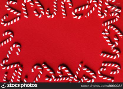 Flat lay Christmas composition with frame of candy canes on a red background. Copy space for text.. Flat lay Christmas composition with frame of candy canes on a red background. Copy space for text