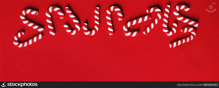 Flat lay Christmas composition with frame of candy canes on a red background. Copy space for text. banner. Christmas composition with frame of candy canes on a red background. Copy space for text. banner
