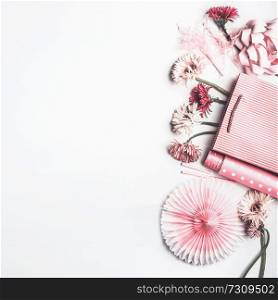 Flat lay composition of pink accessories to female holidays: Mothers day , Womens day, birthday. Paper shopping bag with flowers,paper, party fan and ribbon on white background, top view, border