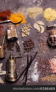 Flat lay composition of various spices and mortars over brown slate background, top view. Flat lay spices